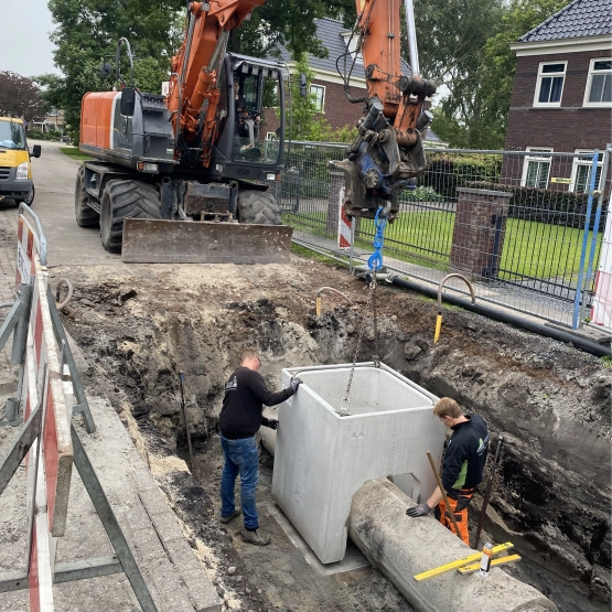 Rioolwerk in een straat met graafmachine en betonnen put