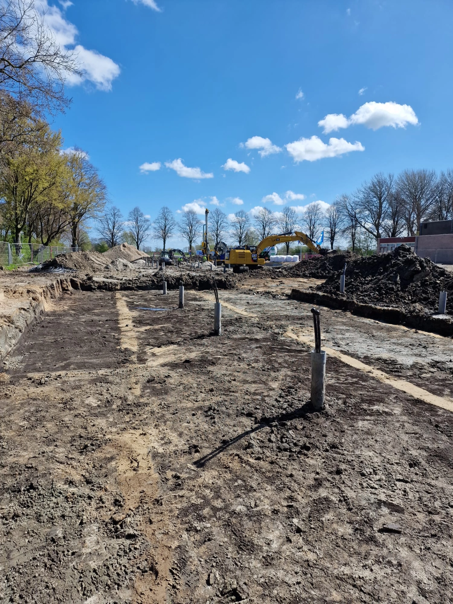 Uitgegraven bouwterrein met leidingen en funderingspalen